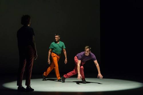 two dancers in a spotlight with a third in the shadow